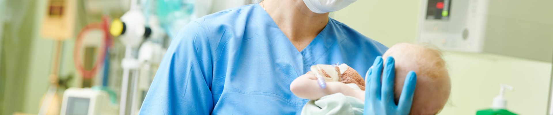 Female nurse holding a newborn baby in hospital. At neonatal resuscitation center